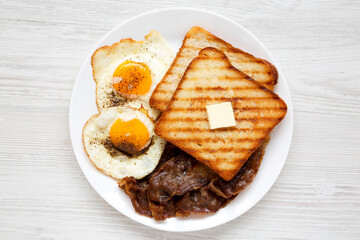 Homemade Healthy Sunnyside Eggs Breakfast on a white plate on a white wooden background, top view. Flat lay, overhead, from above.