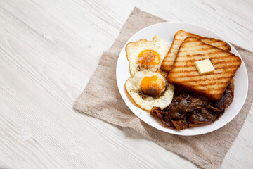 Homemade Healthy Sunnyside Eggs Breakfast on a white plate on a white wooden background, low angle view. Copy space.