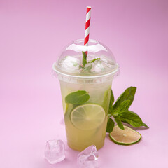 soft mojito in a plastic glass with ice on a pink background