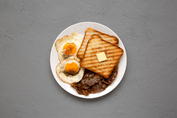 Homemade Healthy Sunnyside Eggs Breakfast on a white plate on a gray background, view from above. Flat lay, overhead, from above.