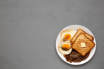 Homemade Healthy Sunnyside Eggs Breakfast on a white plate on a gray background, view from above. Copy space.
