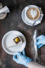 A waitress in medical gloves serves cake and coffee in a cafe after quarantine. Individual protection.