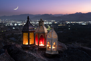 Ramadan lanterns kept on top of the hill against crescent moon with a background of the valley in...