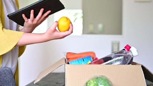 宅配注文した食材の情報をタブレットで確認する女性