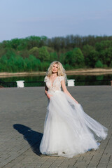 Fototapeta na wymiar Minsk, Belarus - 05.05.2020. Young attractive blonde bride with curly hair walking in the park and smiling