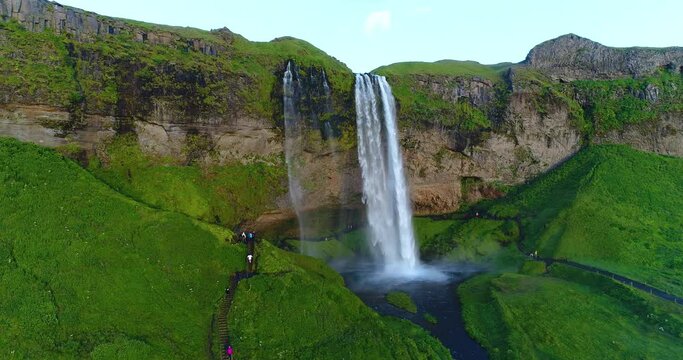 Iceland drone video aerial of famous waterfall Seljalandsfoss in Icelandic nature. Icon tourist attractions and landmark destination in Iceland nature landscape in South Iceland. Unrecognizable people