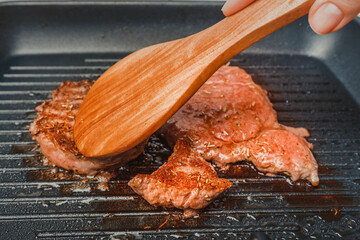 Cooking a raw slice of kobe beef ribeye steak on a raised pan in the kitchen. Delicious homemade...