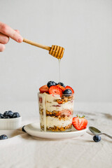 Homemade granola with berries and yogurt in a glass. Healthy eating Granola sprinkled on a white plate with fruit.