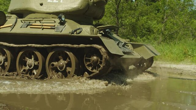military tank t-34 rides through mud in a forest location, moves towards the camera.