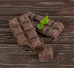Piece of chocolate bars with green mint leaf on a table
