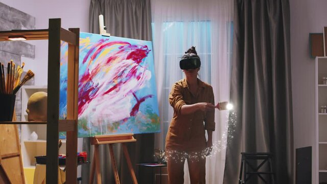 Female painter using virtual reality headset to create next masterpiece. She paints with light trails
