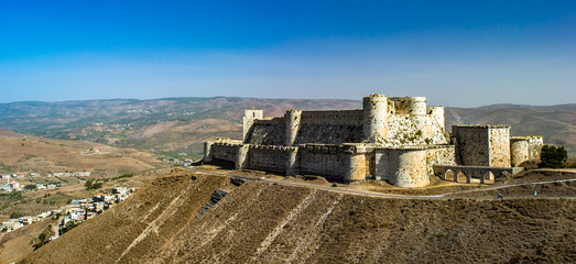 It's Krak des Chevaliers, also Crac des Chevaliers, is a Crusader castle in Syria and one of the most important preserved medieval castles in the world. - obrazy, fototapety, plakaty