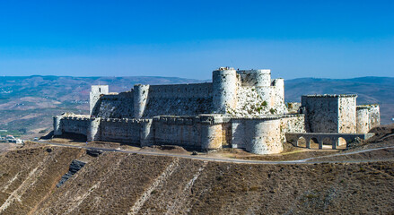 It's Krak des Chevaliers, also Crac des Chevaliers, is a Crusader castle in Syria and one of the most important preserved medieval castles in the world. - obrazy, fototapety, plakaty