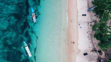 Amazing view of traditional wooden boat on the beach in Pink Beach Lombok, Indonesia. A bird eye photo captured with drone.