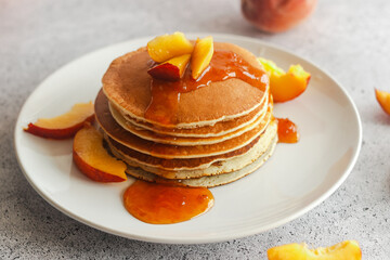 Pancakes with apricot jam and peaches. Pancakes on a plate. Tasty breakfast