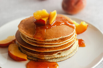 Pancakes with apricot jam and peaches. Pancakes on a plate. Tasty breakfast