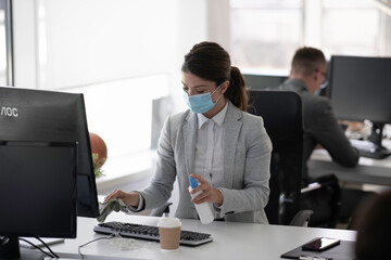 Businesswoman disinfecting her desk in the office.	