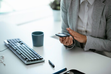 Close up of businesswoman using digital glucometer in office. Young woman checking blood sugar...