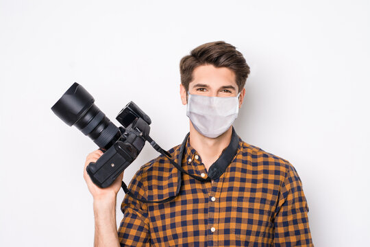 Close-up portrait of his he nice attractive healthy guy holding in hands camera wearing safety mask mers cov infection flu grippe preventive measures isolated over light gray white background