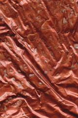 Copper bronze liquid trapped in wrinkle plastic wrap with air bubble