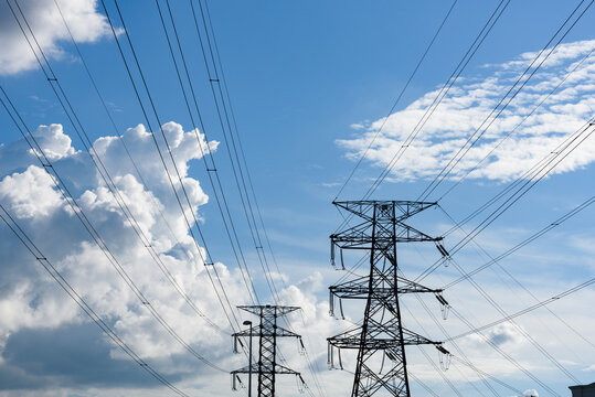 Kuching, Sarawak / Malaysia - August 28, 2017: Power poles and cables silhouetted in blue sky.