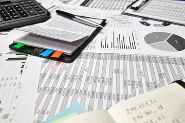 Top view of office employee's desk - work with financial reports, analysis and accounting, tables and graphs, various office items for bookkeeping