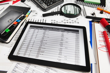 Top view of office employee's desk - work with tablet pc computer and financial reports, analysis and accounting, tables and graphs, various office items for bookkeeping