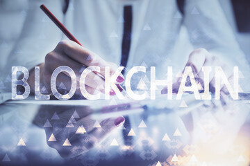 Cryptocurrency hologram over woman's hands writing background. Concept of blockchain. Double...