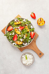 Fresh salad with grilled peaches, strawberries and cottage cheese. Top view. Summer food concept