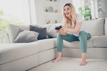 Photo of beautiful cheerful lady relaxing sit comfy couch barefoot positive emotions playing video games stay home quarantine time excited addicted gamer winner victory living room indoors