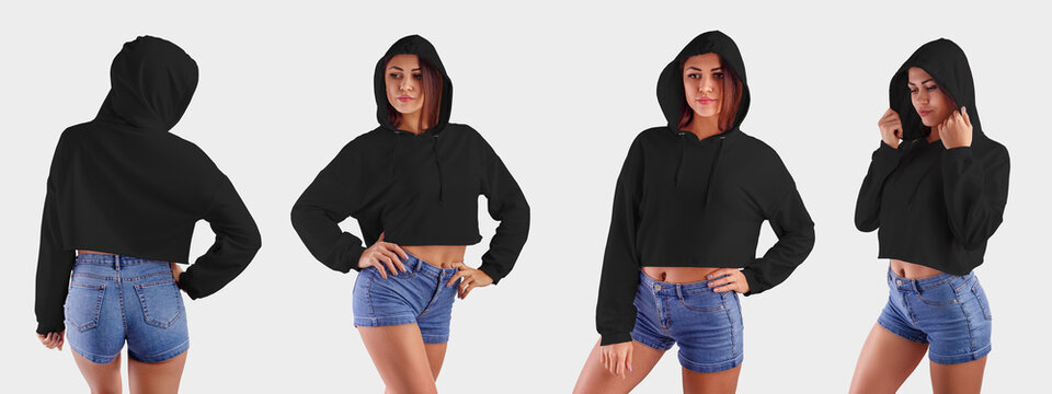 Mockup of a black crop top on a slim girl in blue shorts, standing in the studio on a white background, blank hoodie for design presentation.