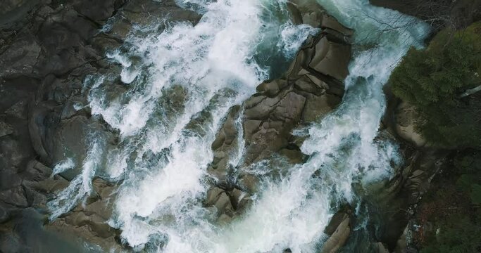 Aerial Vertical View Over The Surface Of A Mountain River Prut, Yaremche, Ukraine. Drone view of waterfall. Turquoise water flows over the stones.