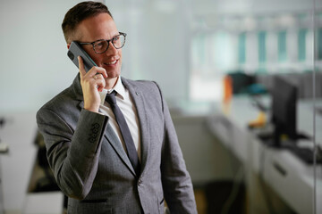 Businessman in office. Handsome man talking on phone at work	