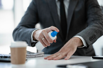 Close up of businessman disinfecting hands in the office.	