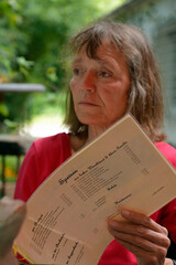 frau liest im gartenlokal die speisenkarte