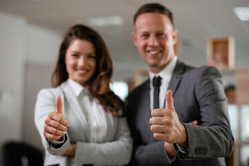 Businesswoman and businessman showing thumbs up.	