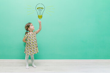 A child shows on a hand-drawn light bulb. Concept for an idea and a young startup. Funny little girl on a turquoise background with a place for text.