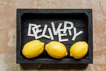 top view of word delivery near lemons in wooden black box on weathered surface