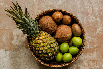 top view of ripe exotic fruits in wicker basket on weathered surface