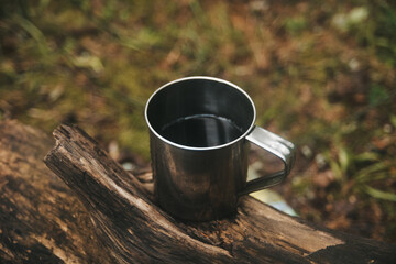 Travel titanium cup on wood. Camping lifestyle.