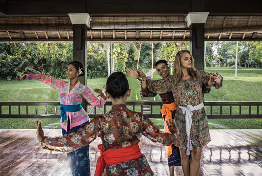 Asia, Indonesia, Bali, young Caucasian woman, enjoying a  traditional Balinese Legong dance class , experiencing local culture with 3 expert Balinese dancers,  hosted inside a traditional  building