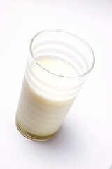 Overhead view of glass of milk on white background .