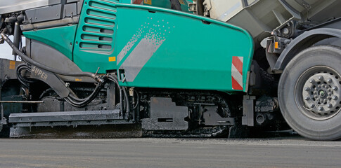 Fototapeta premium Asphaltfertiger wird von LKW mit Asphalt beladen