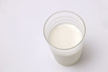 Overhead view of glass of milk on white background .