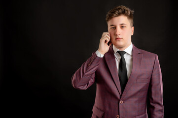 Law student with blond hair dressed in burgundy jacket, white shirt and black tie talking on cellphone