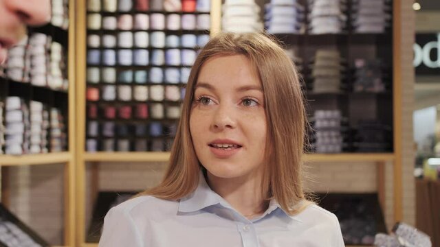 A female consultant helps a client choose a shirt at a branded clothing store.