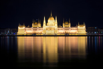 Fototapeta na wymiar Hungarian Parliament building and Danube River in the Budapest city at night. A sample of neo-gothic architecture, Budapest's tourist attraction