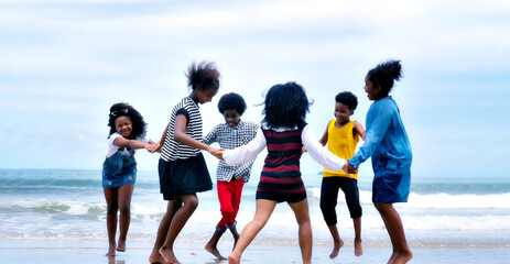 Group Of Young African American Children playing  on the beach.