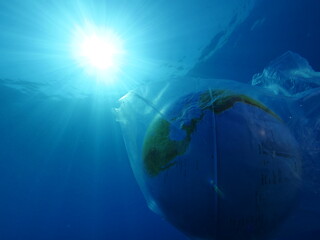 Fototapeta na wymiar world in plastic bag drifting underwater representing ocean pollution with sun beams and rays 