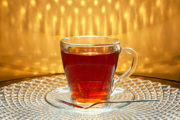 A cup of tea is standing on a glass tray.
